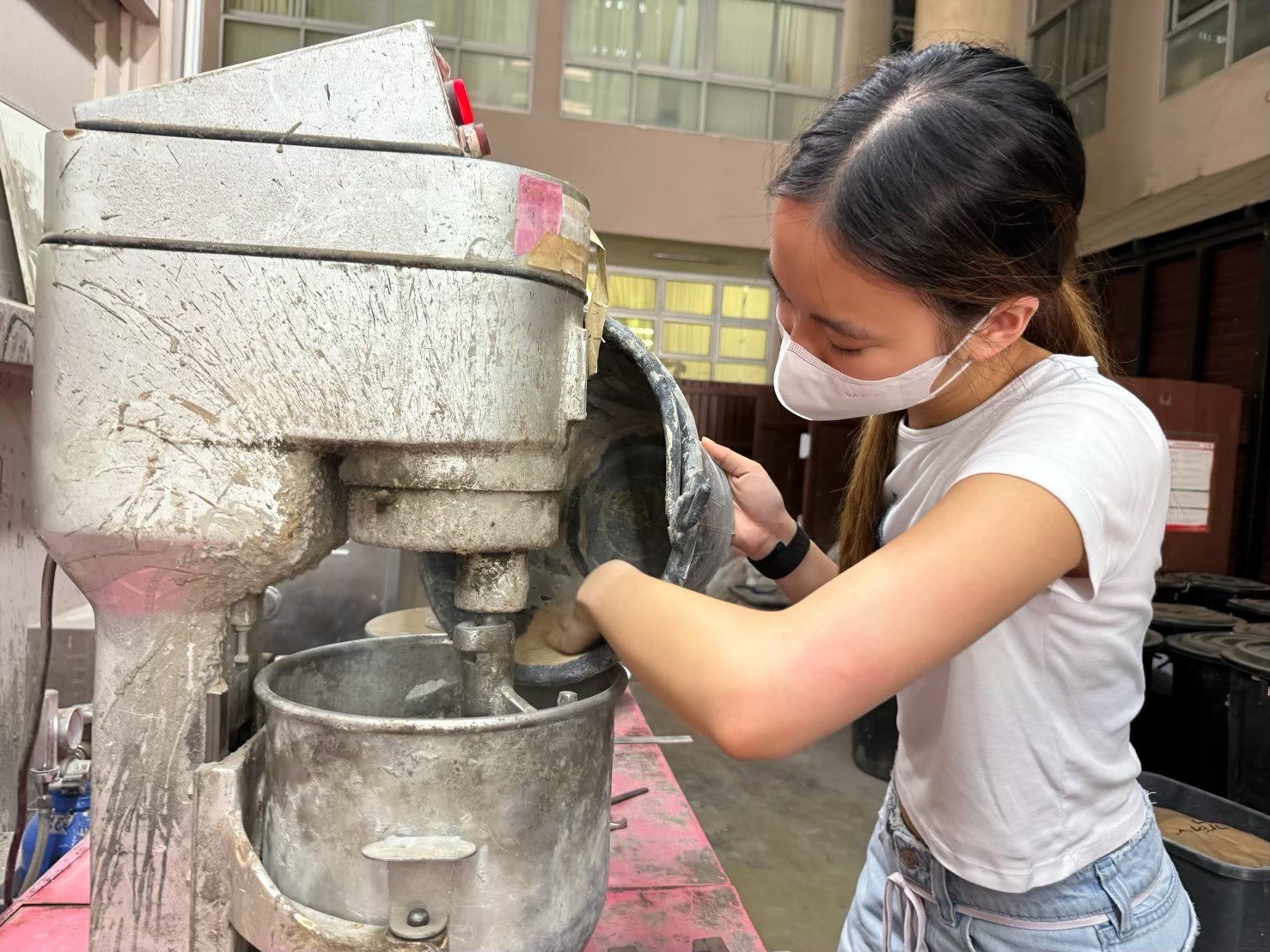 Winnie adding biochar mix into a mortar mixer at the laboratory