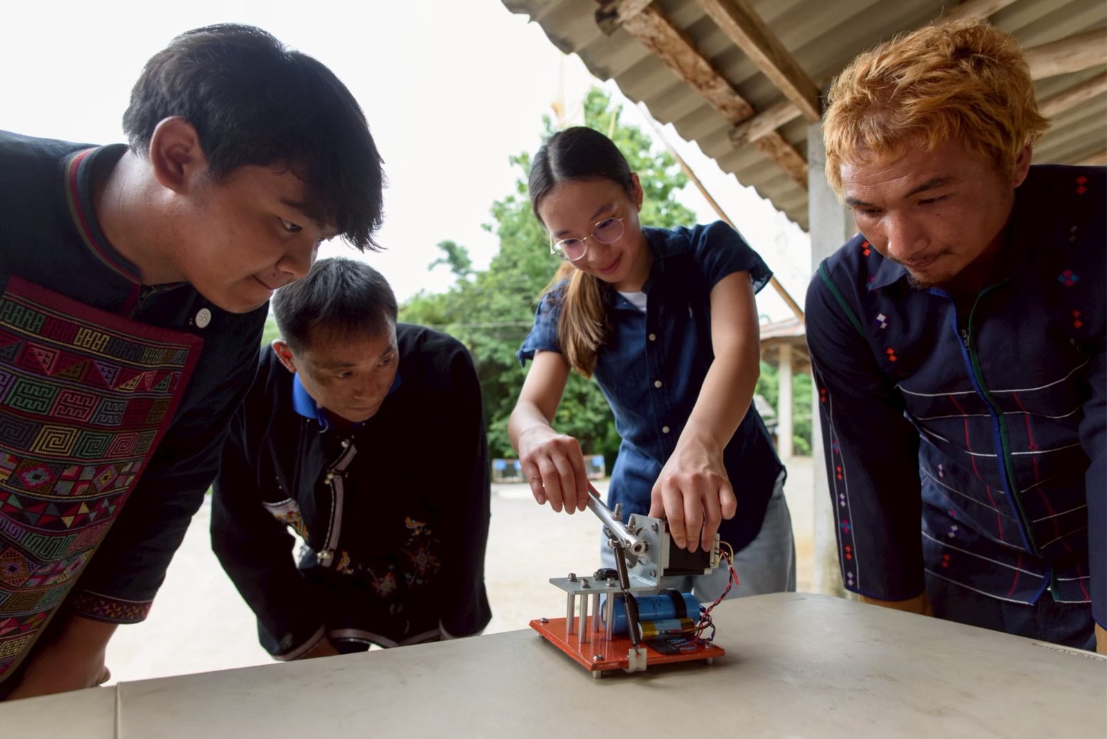 Winnie demonstrating the pedal-powered generator to community members at a village hall in Chiang Rai
