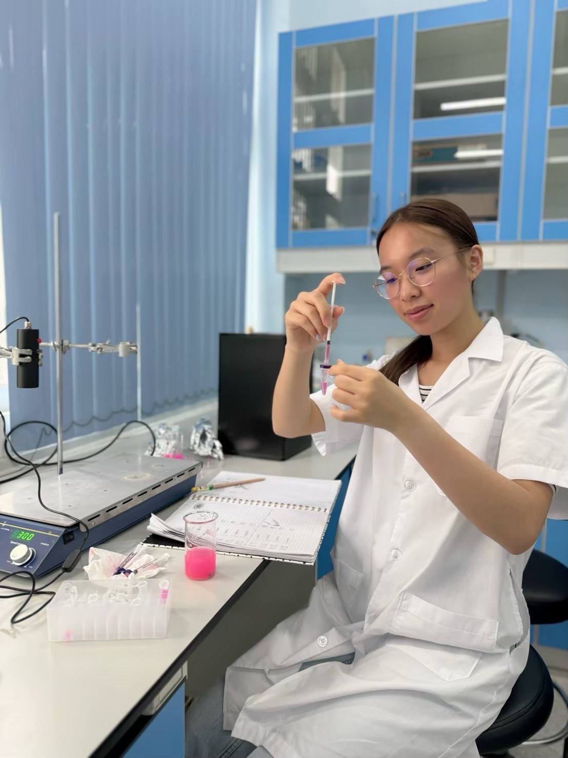 Winnie preparing a sample with a syringe at the laboratory bench